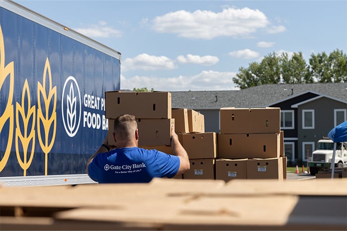 Gate City Bank team member stacking boxes for West Fargo Eats beside truck in West Fargo, ND