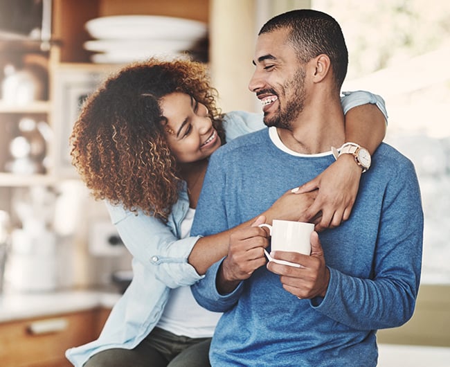Couple smiling at each other in the kitchen of their new home, thanks to help from a Fargo mortgage lender at Gate City Bank