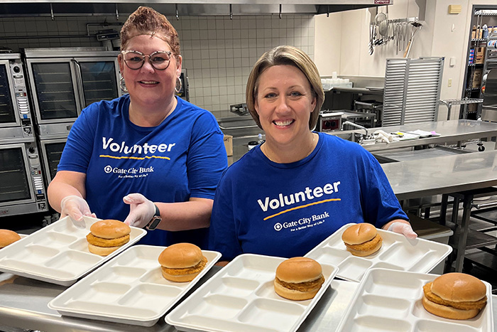 Gate City Bank volunteers Michelle Neumiller and Jacque Erickson smile while serving sandwiches at Jamestown Middle School