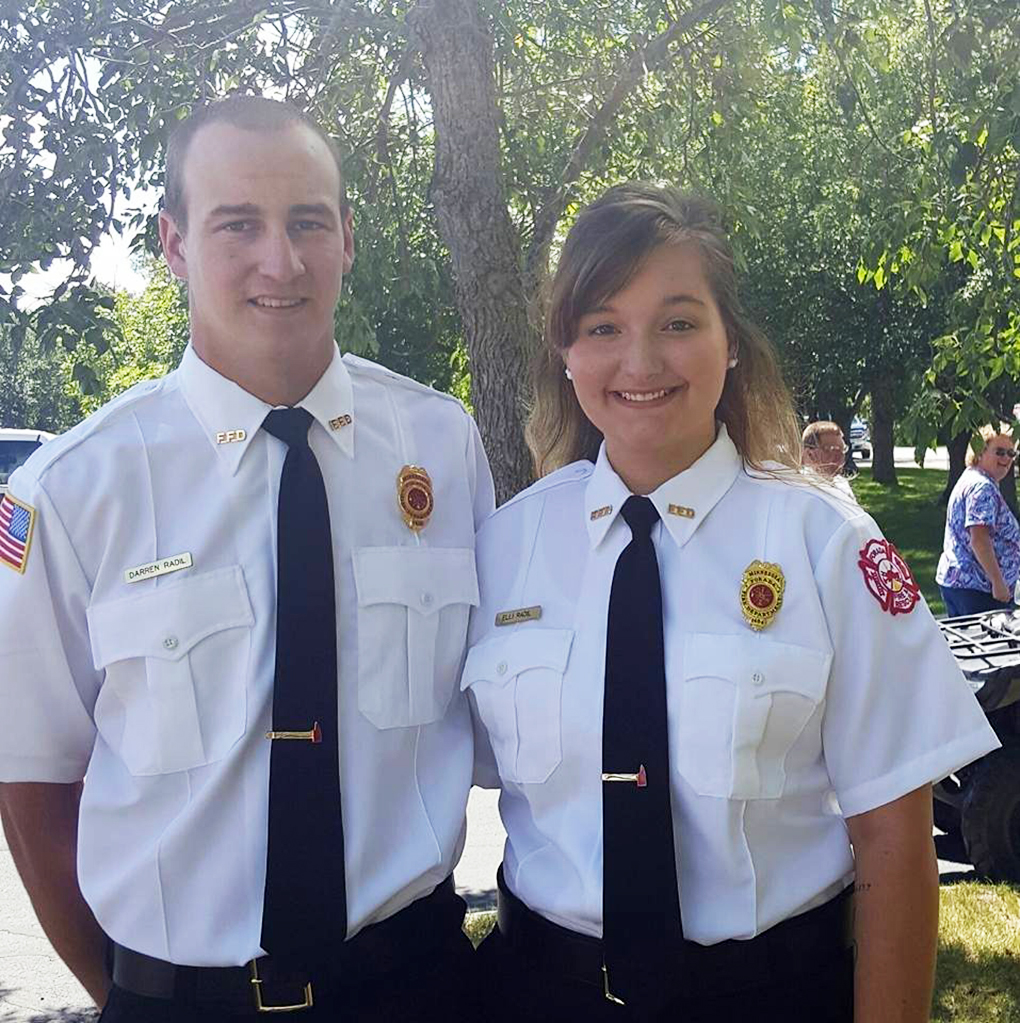 Elizabeth and Darren Radil pose together in their first responder uniforms on a sunny day