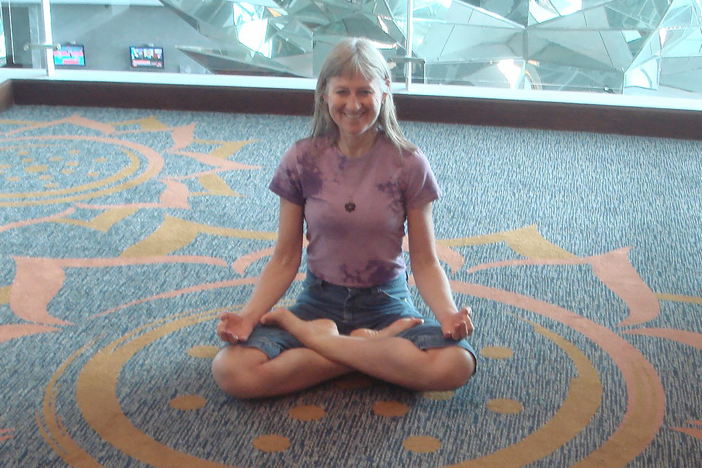 Brenda J. Haugstad smiles while sitting on the floor to do yoga and meditation