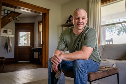 a veteran sits down in his living room & smiles onward after learning about 7 financial military benefits from Gate City Bank