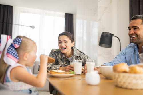 female military member smiles at patriotic young girl at the dinner table