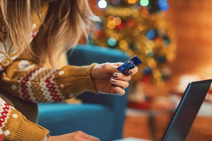 Young lady from Minnesota holding her Gate City Bank debit card while shopping on her computer for black Friday deals