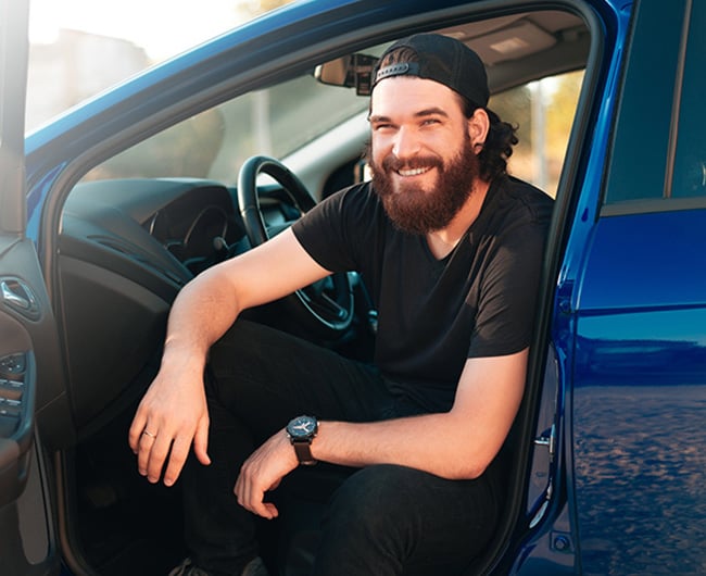Young man sitting in the driver’s seat of his new vehicle after getting an auto loan from Gate City Bank in Minot, ND.