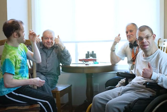 special-needs clients and roommates of Creative Care for Reaching Independence give a thumbs-up for the camera from the kitchen of their home