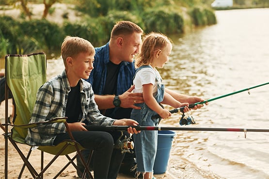 father fishes with child in the sunshine and laughs as he avoids fraud attempts with tips from gate city bank