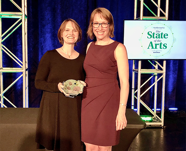 Karin Rudd smiles for the camera on stage while receiving the outstanding advocate for the arts award in 2021