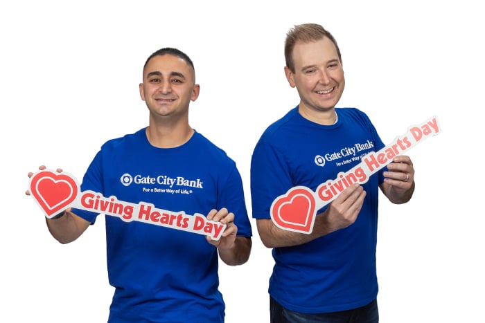 Gate City Bank team members hold Giving Hearts Day signs and smile for a good cause