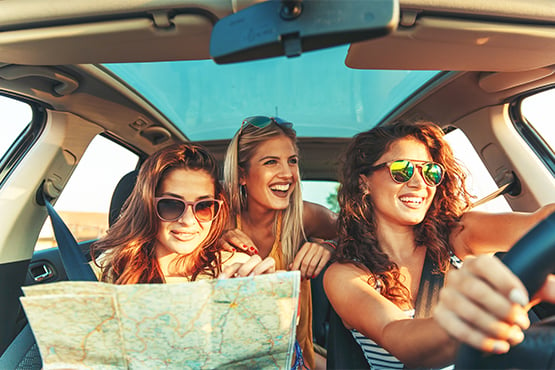 Three happy young woman on a summer road trip, driving a new car purchased with a Gate City Bank auto loan in North Dakota