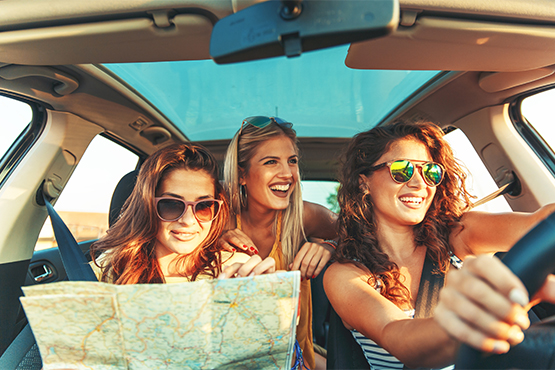 Three happy young woman on a summer road trip, driving a new car purchased with a Gate City Bank auto loan in North Dakota