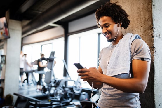 young man at the gym checking his savings balance on his mobile app