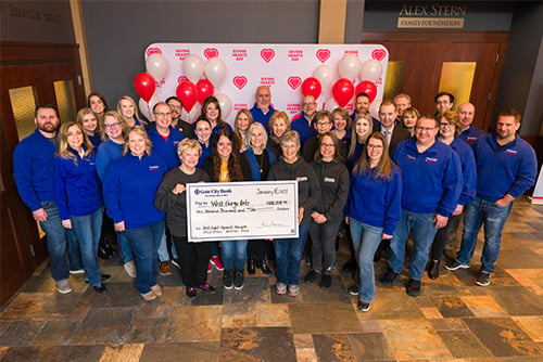 a group of Gate City Bank team members wearing matching blue gather around a big check made out for $100K to West Fargo Eats