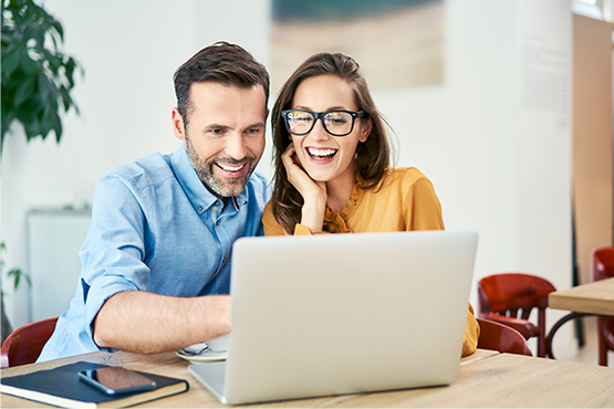 a happy couple sits next to a laptop and explores helpful financial education resources from Gate City Investment Services