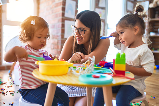 Female daycare provider plays at home with children after receiving approval for Better Life Child Care Business Loan from Gate City Bank