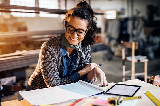 woman business owner looks at tablet and papers while enjoying benefits of business CD