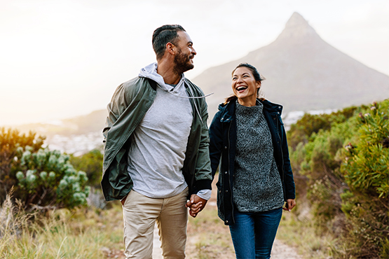 Relaxed middle-aged couple on their dream vacation, holding hands and hiking through the mountains