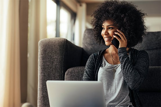 woman looks on and smiles while on the phone and enjoys Gate City Bank savings