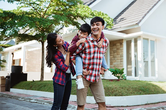 relaxed  couple in plaid shirts laughing in front yard with 8-year-old son, breathing easy after refinancing their mortgage