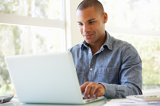 happy man sits at table with laptop and enjoys helpful educational resources