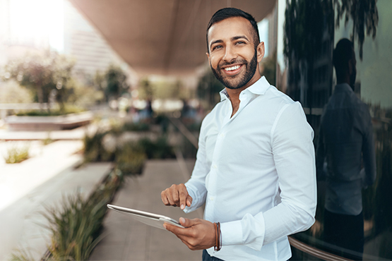 happy male entrepreneur holds laptop outside and enjoys his business savings account