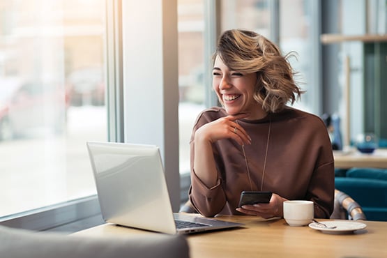 laughing young woman on phone at coffee shop enjoys peace of mind with gate city bank emergency savings account