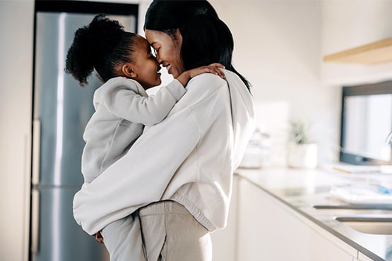 Mom touches noses with her 6-year-old daughter in their new white kitchen in Fargo, ND, thanks to a Gate City Bank home loan