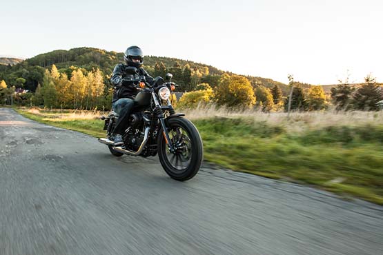 motorcycle rider cruises a backroad at sunset