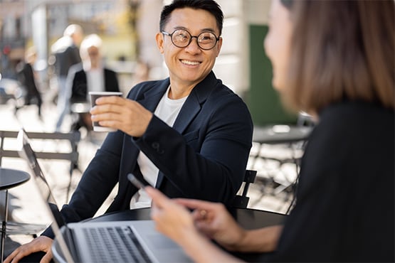 happy man holds coffee cup and enjoys a conversation with friend about how to prevent overdraft fees with gate city bank