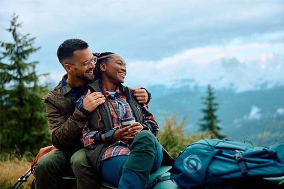Happy hiking couple from ND, relaxing on a mountainside while their high yield savings account grows with Gate City Bank