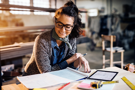 woman business owner looks at tablet and papers while enjoying benefits of business CD