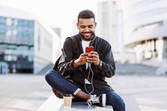 happy man in coffee shop uses phone for Gate City Bank’s payment methods