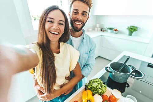 happy young couple takes a selfie in their new kitchen after going through first-time homebuyer steps with Gate City Bank