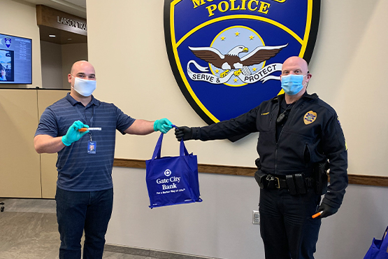 a Gate City Bank team member hands hand sanitizer to a police officer