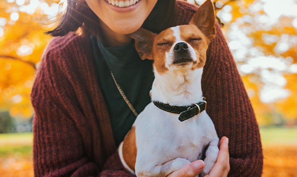 Smiling brunette, holding her cute terrier up to the camera for a photo outside Gate City Bank in Moorhead