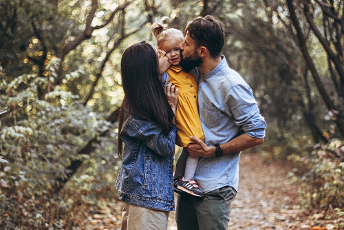 Two Canadian parents kissing their daughter on the cheek while taking a walk in rural Minnesota