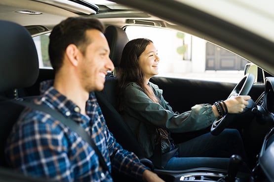 Teenage girl driving her first car with her dad after getting an auto loan from Gate City Bank.