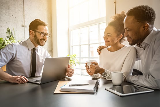 Friendly male insurance advisor talks with a young couple, going over a simple annual insurance coverage checklist
