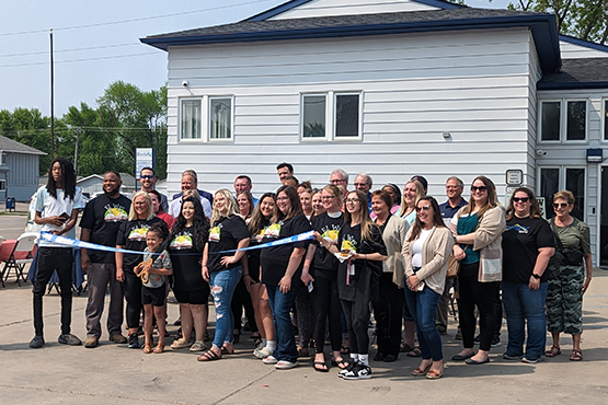 A big group poses for a ribbon-cutting photo in front of El Way Child Care and Learning Center, a day care in Grand Forks, ND