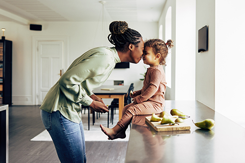 Loving mom touches noses with her young daughter in their kitchen after buying a new home in MN with Gate City Bank