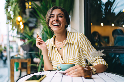 Happy young woman at a coffee shop in Elk River, MN, ready to open her new checking account with Gate City Bank