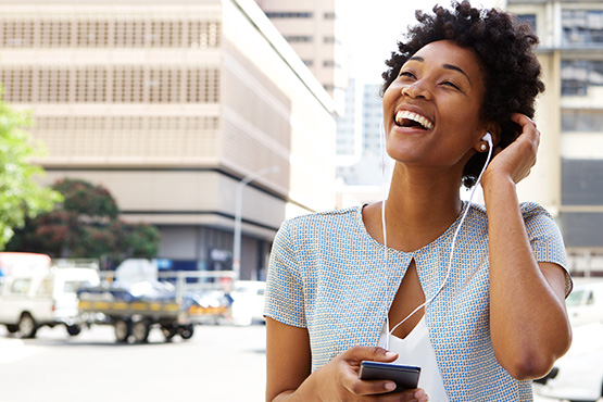 woman happy about interest-bearing checking account listens to headphones outside