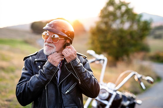 silver-haired biker at sunset in ND, unbuckling his helmet after riding a chopper thanks to a Gate City Bank motorcycle loan