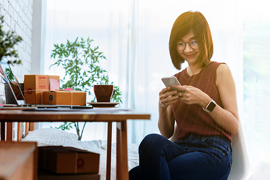 happy woman sits at table with phone to enjoy business money market savings account