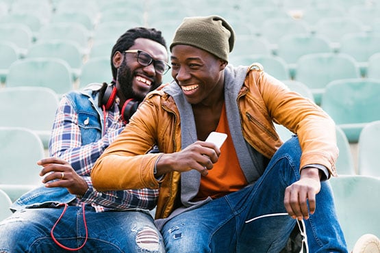 man in a beanie laughing as he refers a friend, telling him all about the perks of checking with Gate City Bank