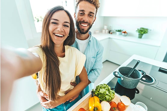 happy young couple takes a selfie in their new kitchen after going through first-time homebuyer steps with Gate City Bank