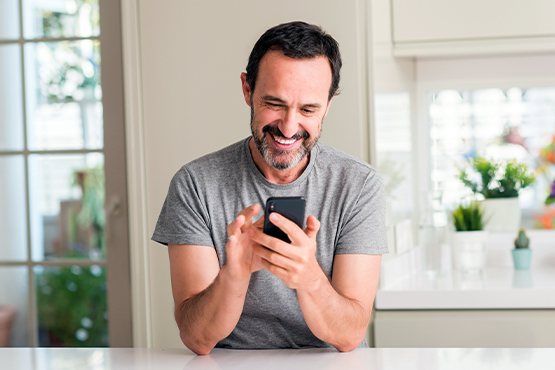 happy man in light gray t-shirt holds his smartphone and avoids scammers while banking