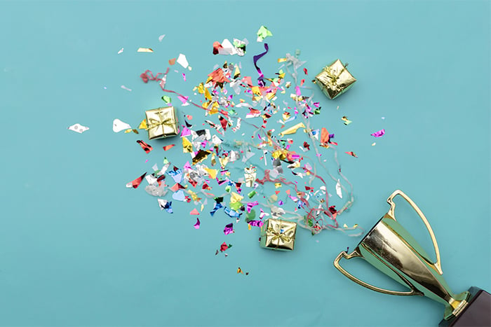 confetti bursting out of a trophy on a light blue background