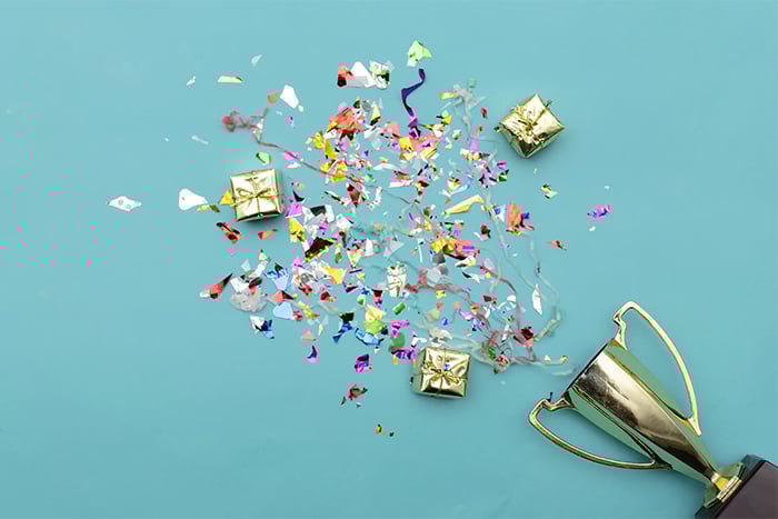 confetti bursting out of a trophy on a light blue background