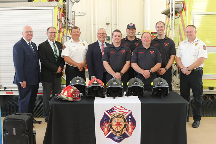 Gate City Bank leaders and West Fargo firefighters pose with new protective helmets